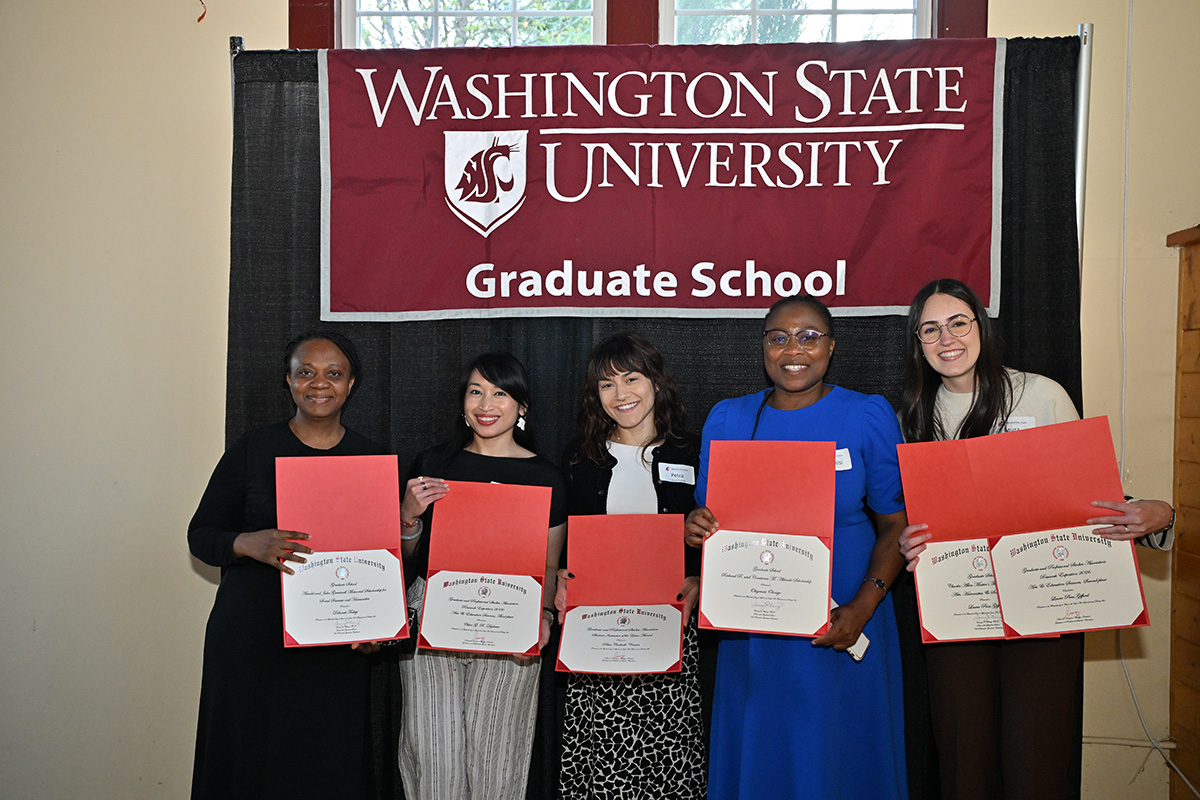 group of students with certificates in front of WSU graduate school flag